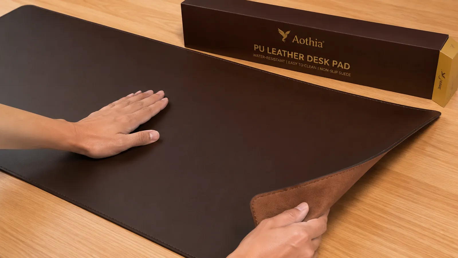 Hand smoothing out a leather desk pad on a wooden desk surface